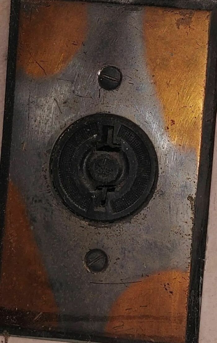Close-up of a rusty, worn electrical outlet cover found in an abandoned home with disturbing and weird objects.