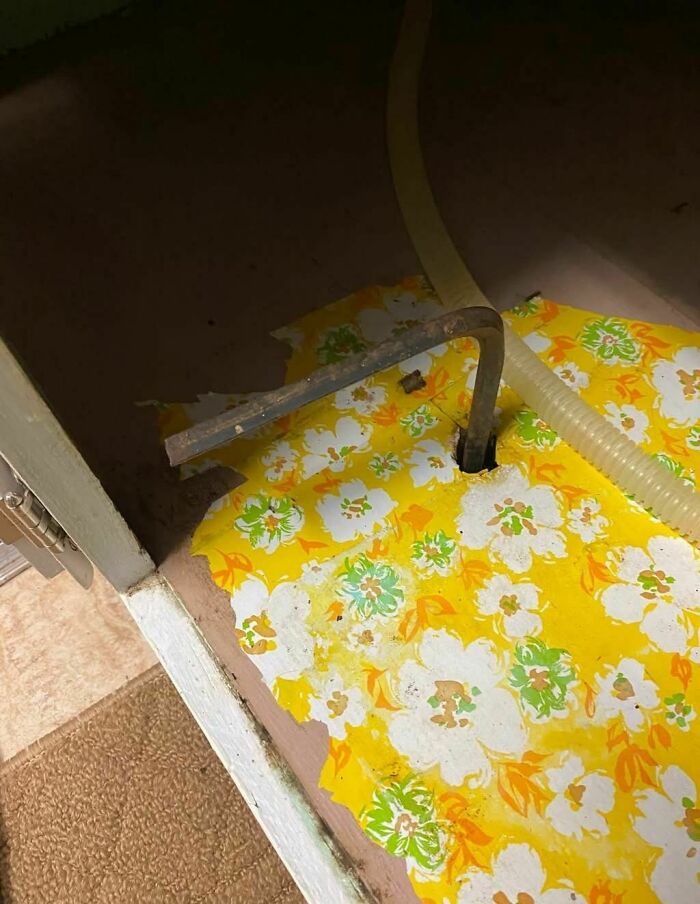 Rusty bent pipe emerging from torn yellow floral wallpaper in an abandoned home with disturbing and weird things found.