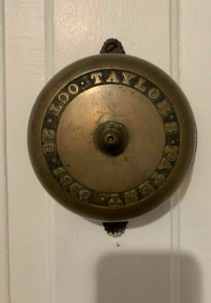 Old tarnished brass bell with engraved text found in abandoned home, showcasing disturbing and weird forgotten objects.