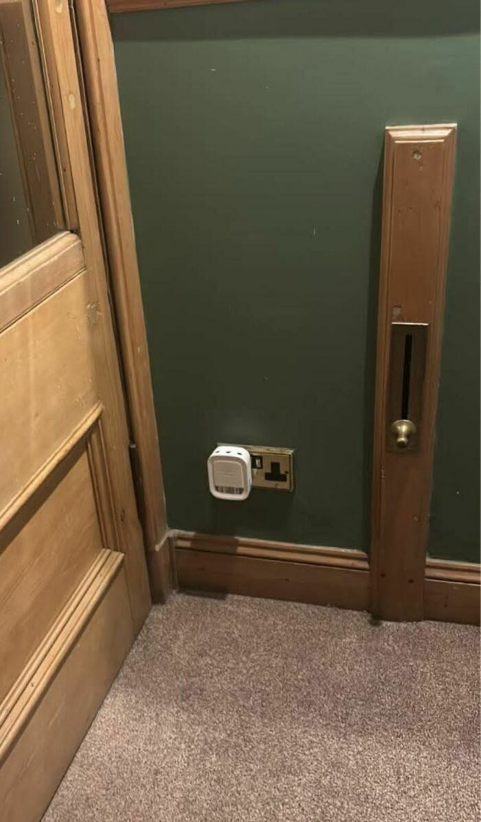 Old room corner with wooden door, unusual wall vent, and an electrical outlet, one of the weird things found in abandoned homes