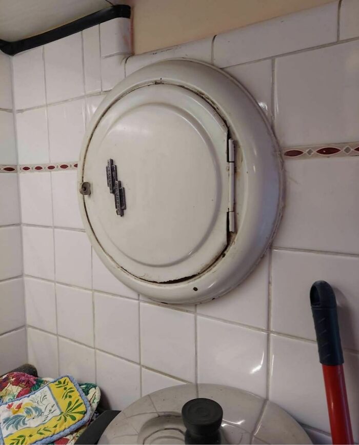 Round vintage laundry chute door in tiled room, a disturbing and weird thing found in abandoned homes.
