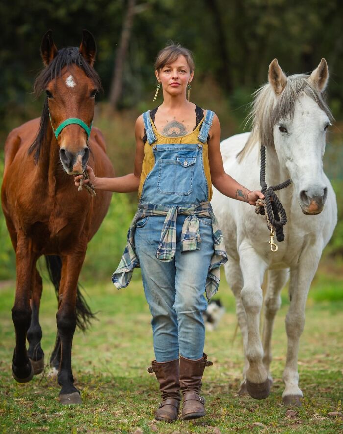 Woman in denim overalls holding reins of two horses, representing ladies choosing power tools and lab coats over manicures.
