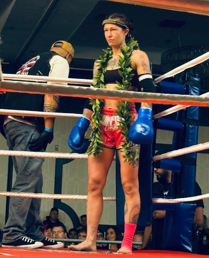 Female fighter in boxing ring wearing blue gloves and a green laurel, representing empowered ladies choosing power tools and lab coats.