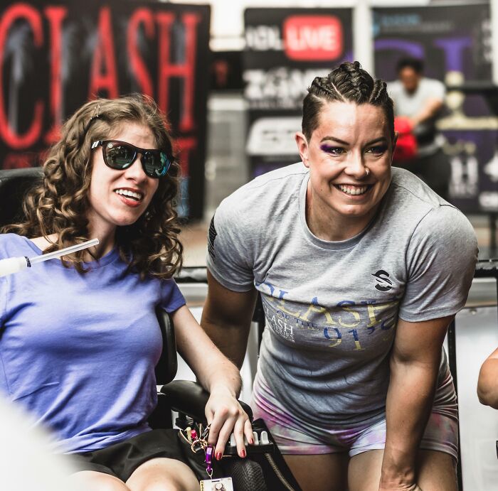 Two women smiling and interacting, representing ladies choosing power tools and lab coats over manicures at an active event.