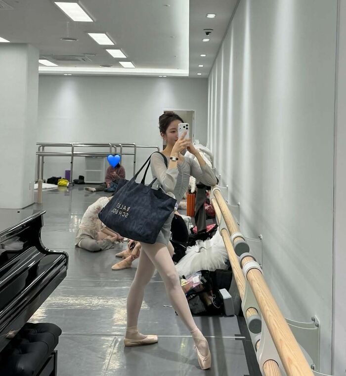 Ballerina in a dance studio taking a mirror selfie, showcasing confidence beyond traditional beauty norms for women.