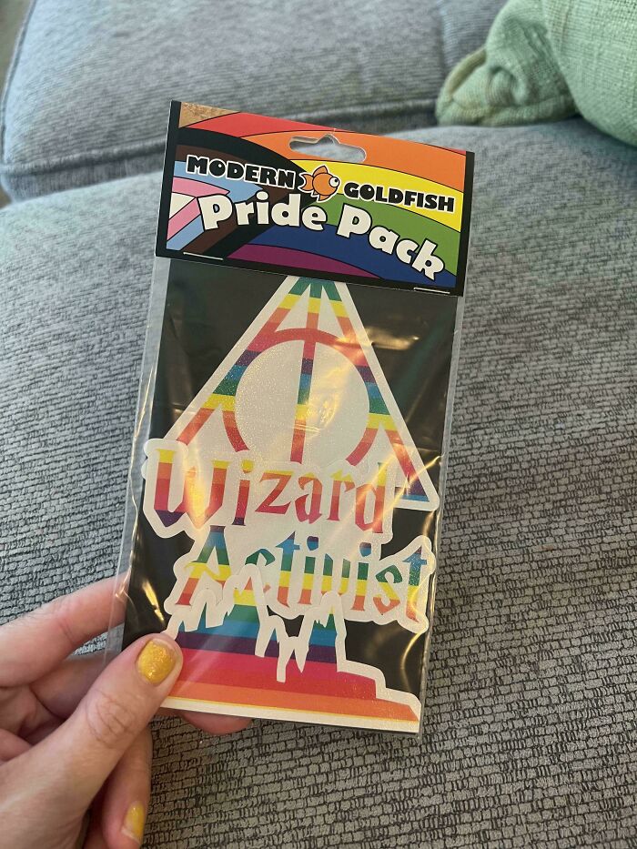 Sticker pack with pride colors and text wizard activist held against a gray fabric background in old photos facepalm collection.