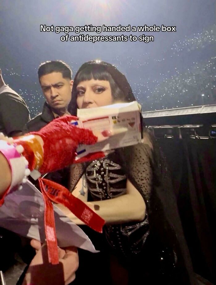 Lady Gaga at an event, appearing surprised as she is handed a box of antidepressants to sign. Funny and unpredictable sentences.
