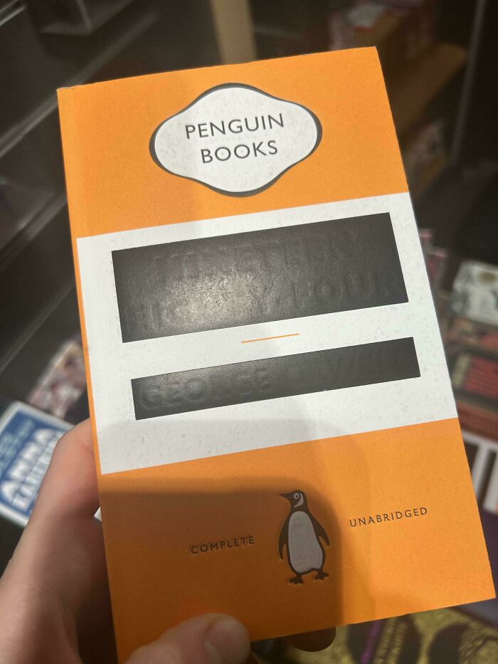A hand holding a Penguin Books cover with redacted text, one of many mildly interesting pictures.