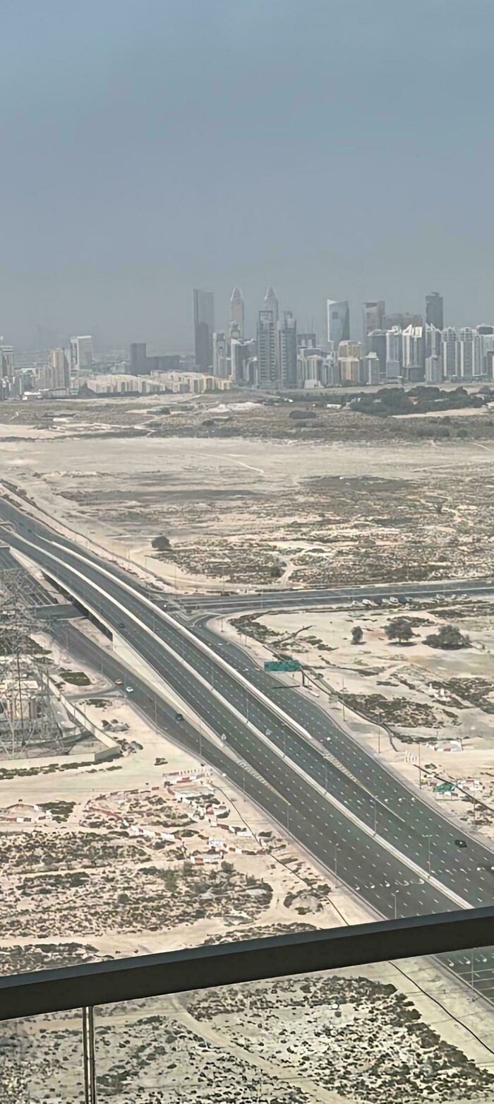 A mildly interesting picture showing a highway leading to a city skyline on a hazy day.
