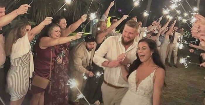 Wedding celebration with couple walking under sparklers held by guests morbid curiosity