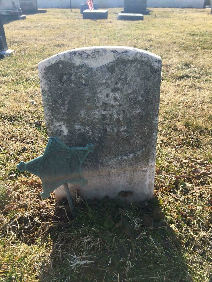 Old weathered tombstone with a metal sheriff star in a graveyard morbid curiosity