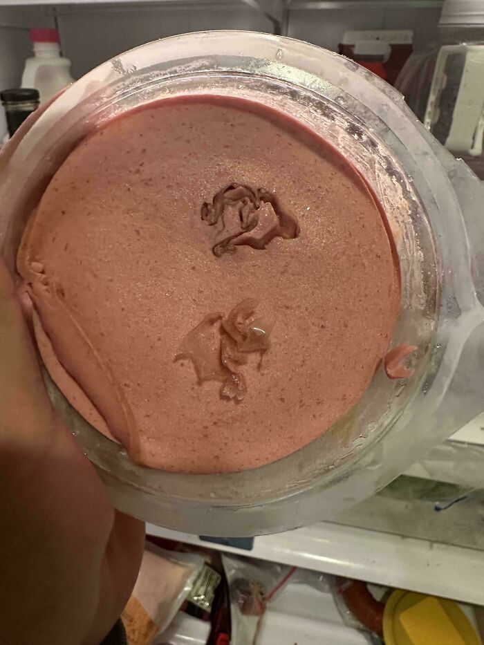 A baffling image of a pink substance in a container, with two strange shapes carved into its surface.