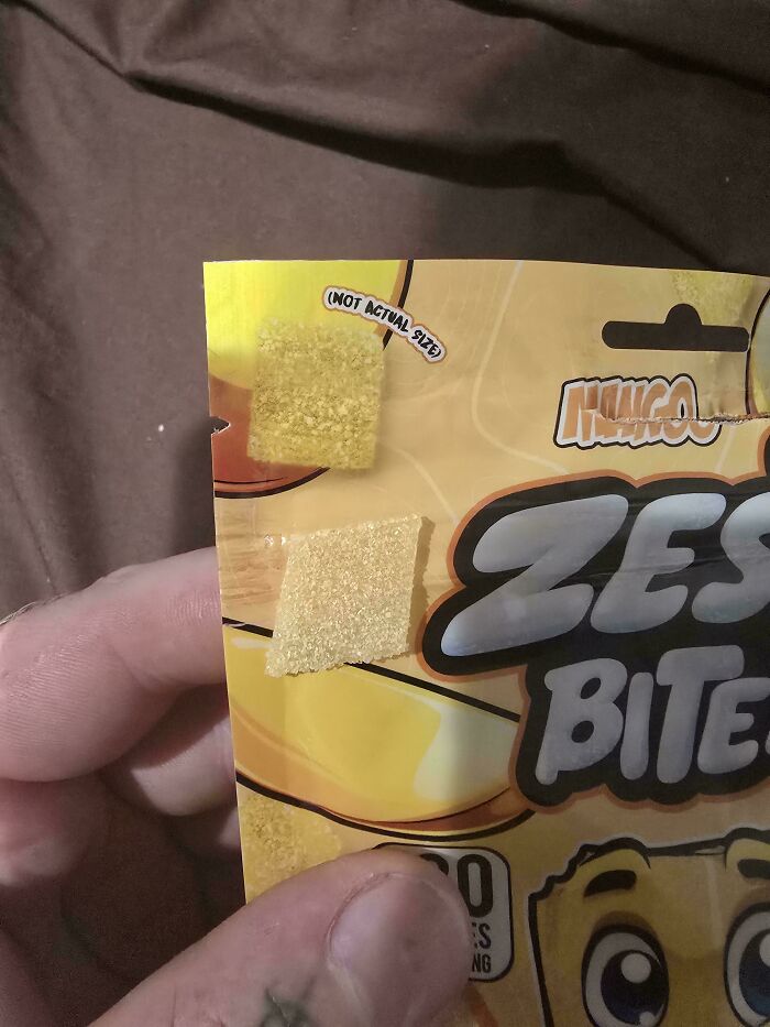 A hand holding a package of Zesty Bites candy, with baffling images of the candy showing not actual size.