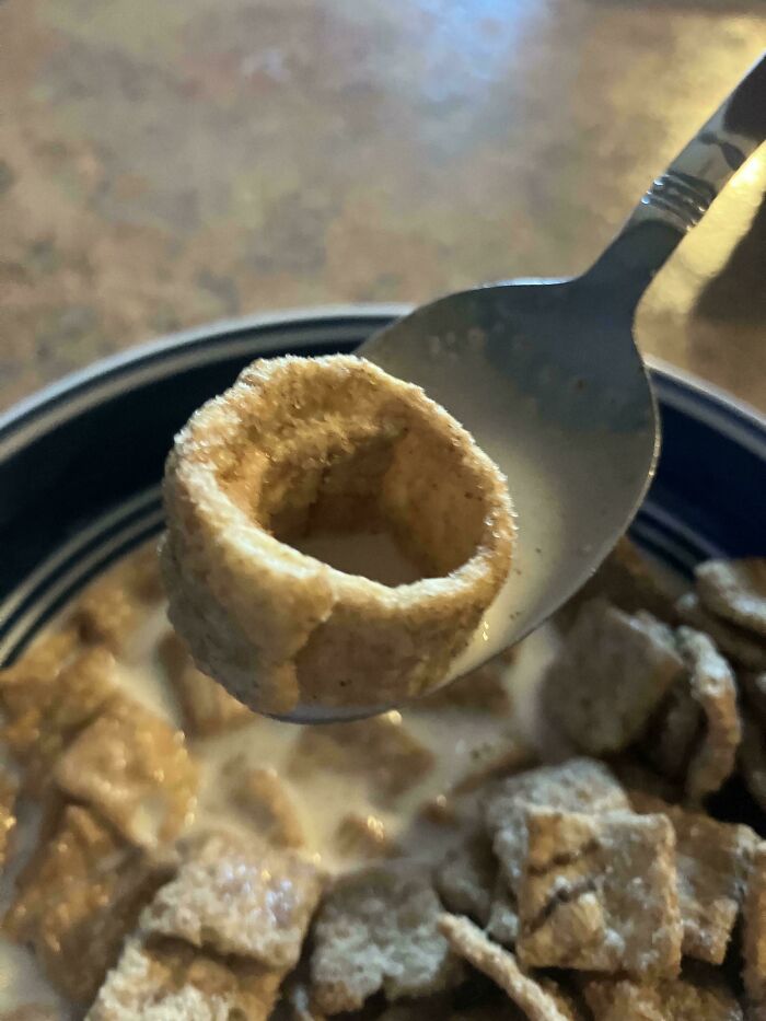 A baffling image of an unusually large, hollow, ring-shaped cereal piece on a spoon.