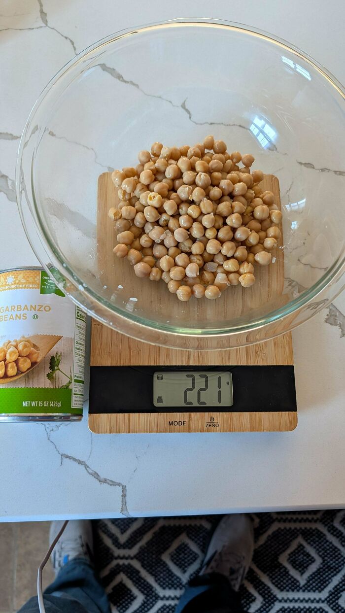Glass bowl of garbanzo beans on digital kitchen scale showing 221 grams