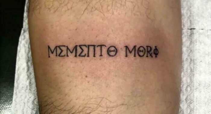 Tattoo fail of a phrase with incorrect Greek letters on skin