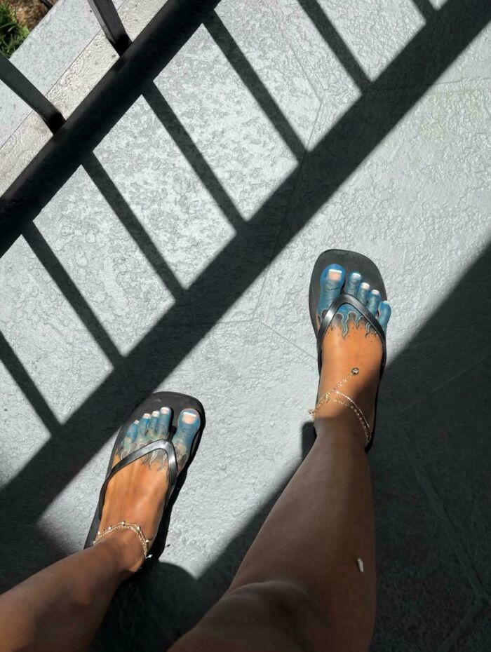 Tattoo fail with toes painted blue and black flip flop sandals outside