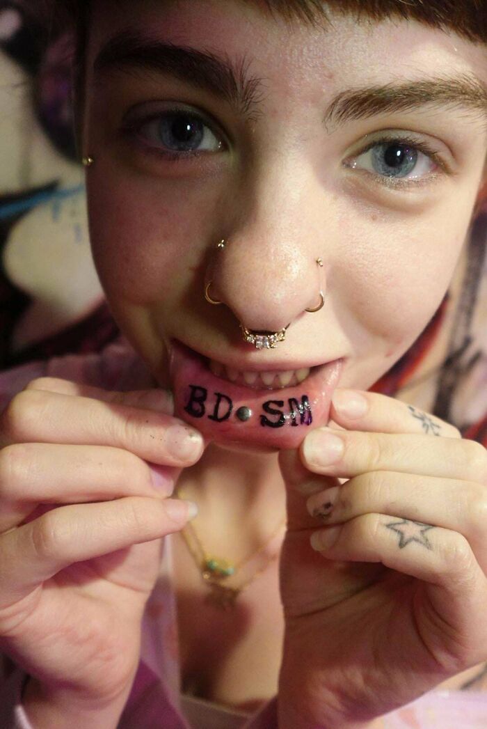 Tongue tattoo fail showing misspelled black lettering smile