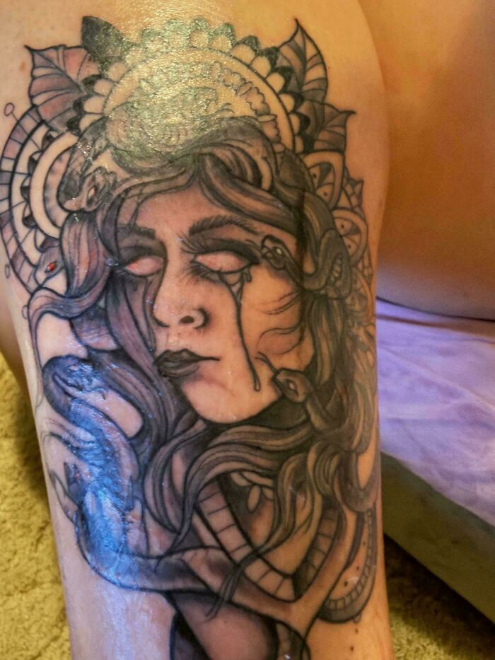 Black tattoo of a woman's face and snakes on arm