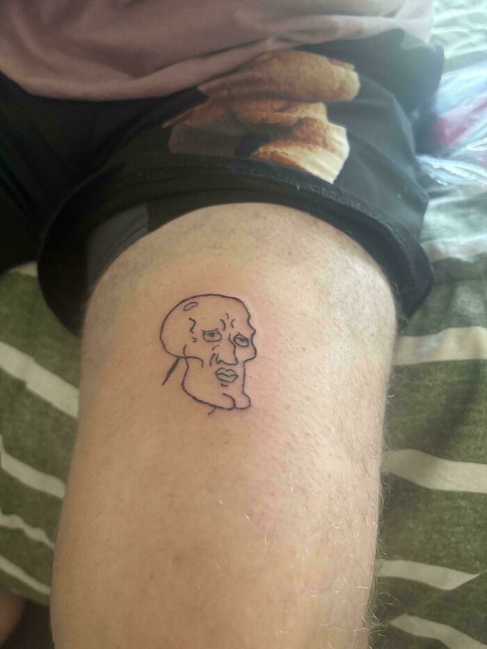 Small outlined face tattoo on leg showing a funny tattoo fail