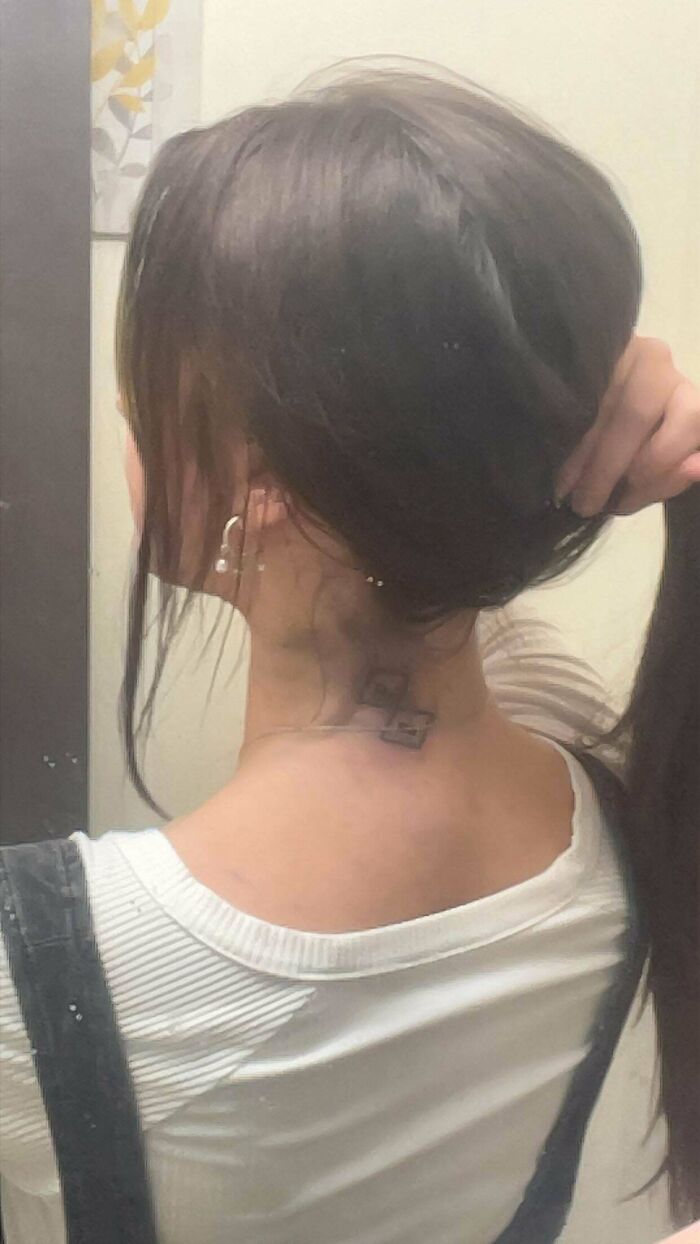 neck tattoo of two small unclear shapes on a woman