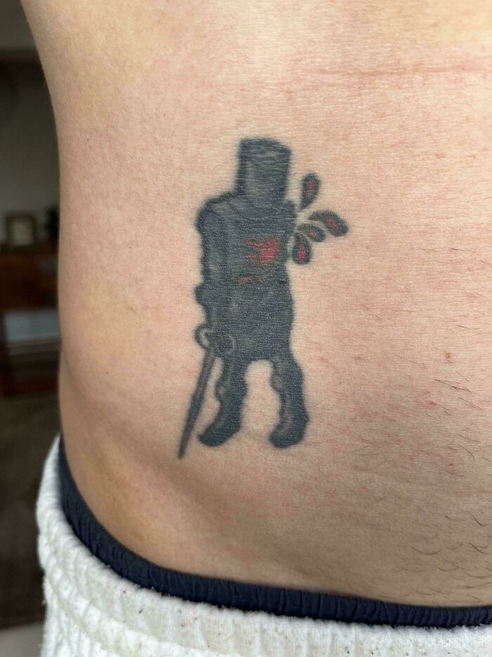 Black tattoo fail depicting a walking figure with unclear details