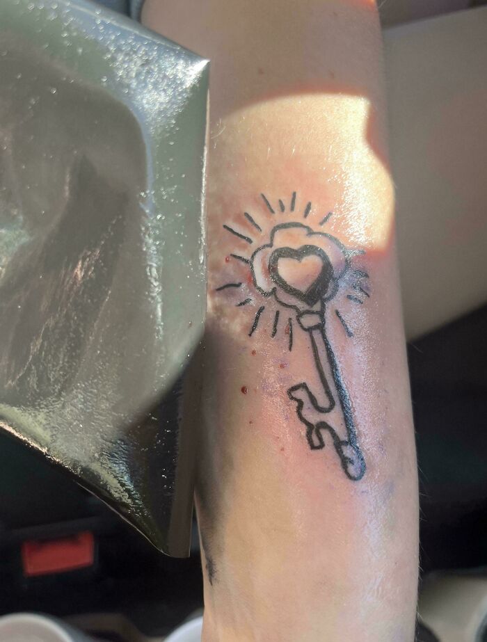 Arm tattoo fail of a simple key with heart and rays in rough style