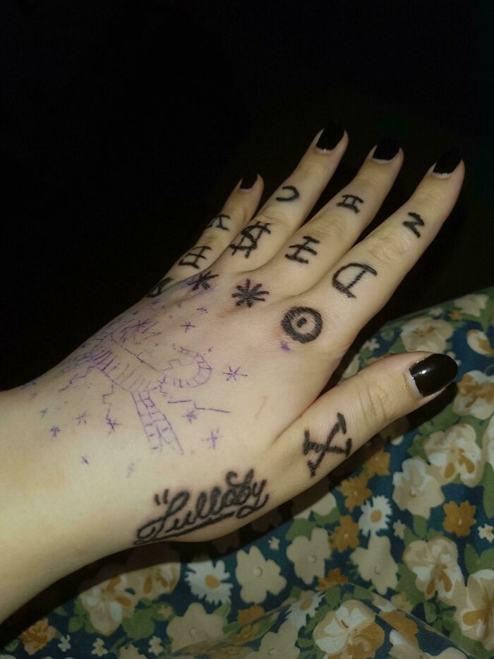 Hand tattoo fail with random symbols and poorly sketched scorpion