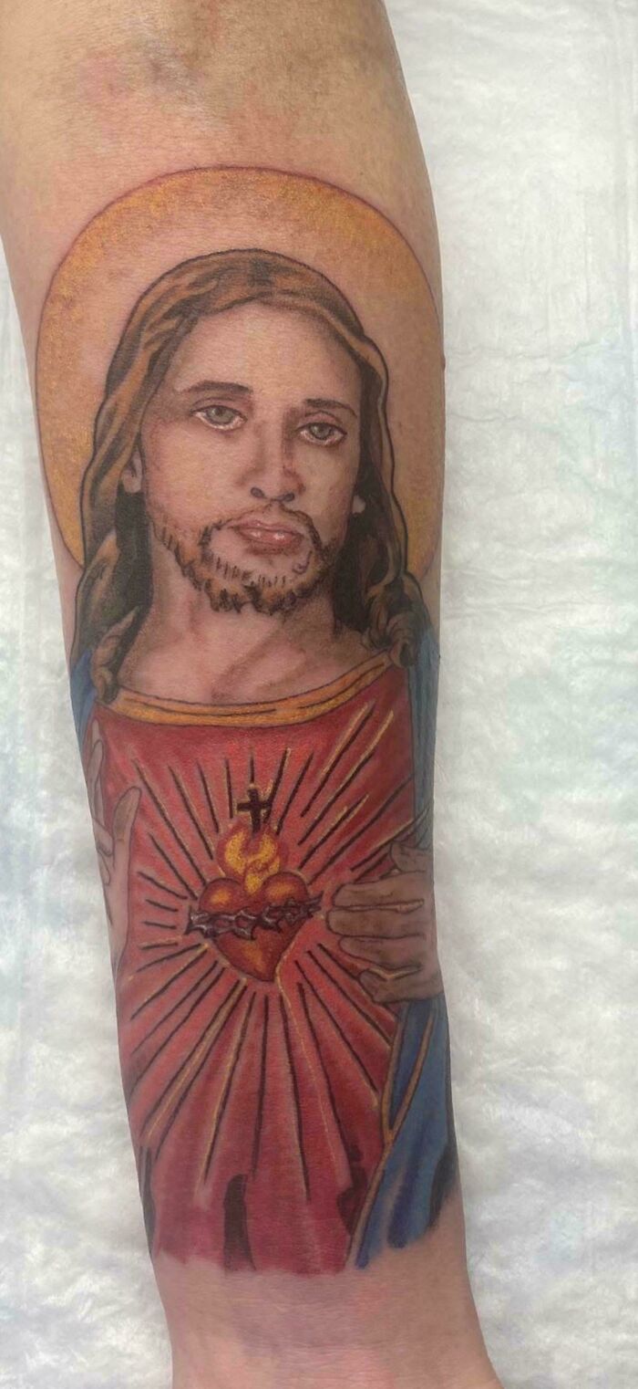 Tattoo fail of a religious heart and figure with awkward facial features
