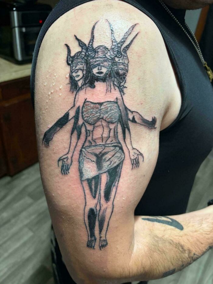 Tattoo fail showing distorted three-headed woman on upper arm
