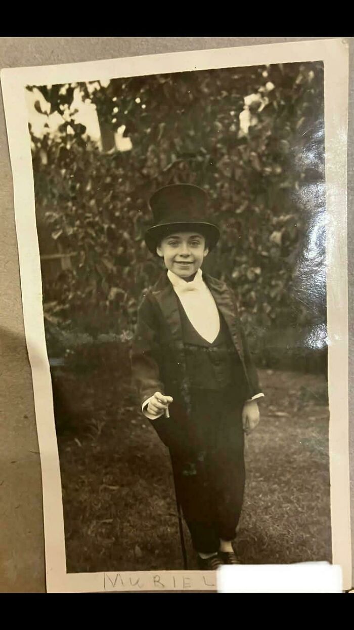 Vintage black and white photo of a child in formal attire and top hat, showcasing a nostalgic scene from decades ago.