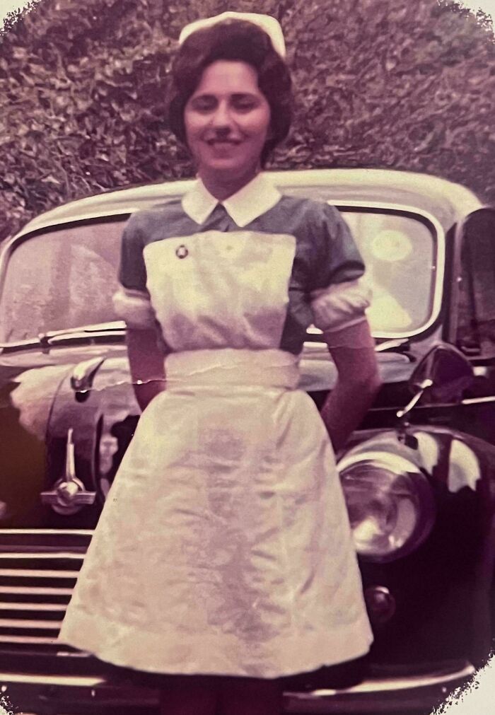 Vintage photo of a nurse in uniform standing in front of a classic car, showcasing powerful decades-old moments.