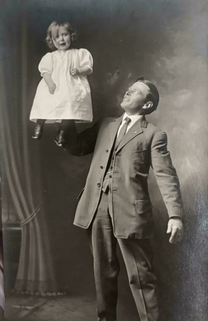 Black and white vintage photo of a man in a suit holding a young child, from decades ago in historical photos.