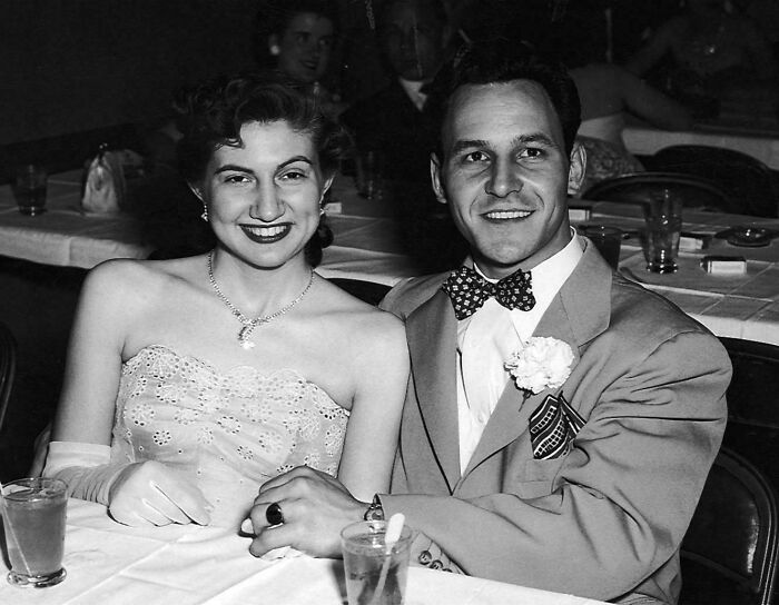 Vintage black and white photo of a smiling couple at a formal event, capturing moments from decades ago.