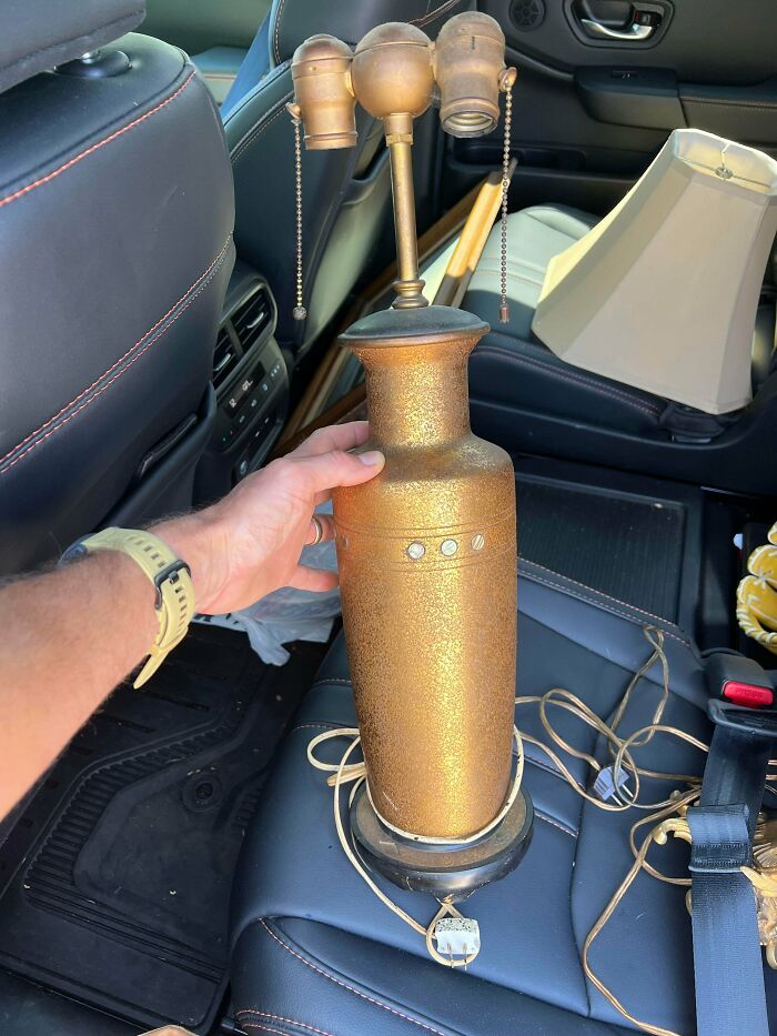 A vintage golden lamp, a remarkable antique, being held by a hand, ready to be refurbished.