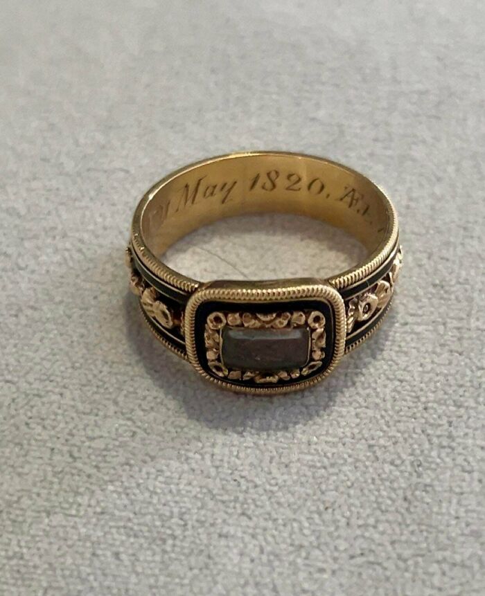 A gold ring engraved May 1820, a remarkable antique with a rectangular dark stone in the center, on a grey background.