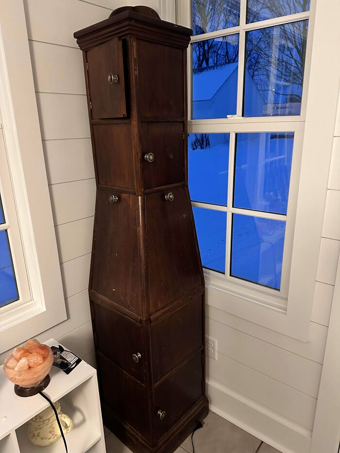 A tall, dark wooden cabinet with a unique tapered design and multiple doors, a remarkable antique furniture piece.