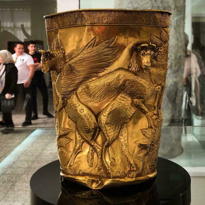 Ancient gold vessel decorated with winged mythical creatures displayed in museum