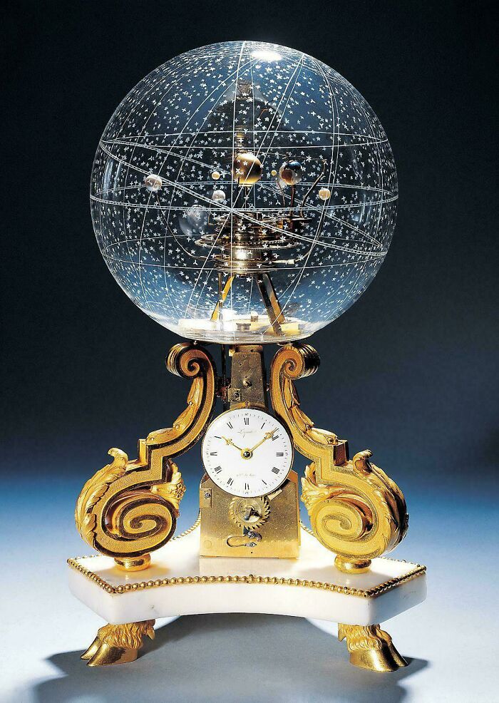 Antique orrery clock with celestial sphere showing star constellations and planetary orbits