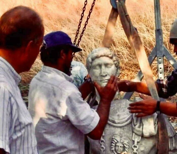 Archaeologists examining a newly uncovered bust statue at a historic discovery site