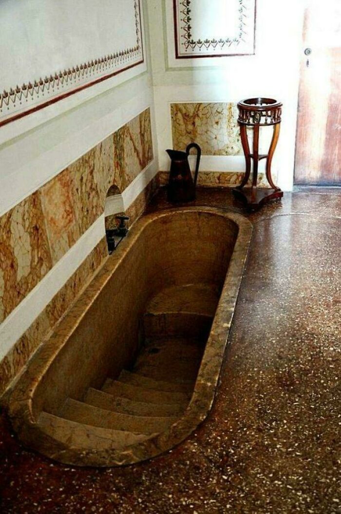 Ancient stone bathtub with elegant wall design in historical building
