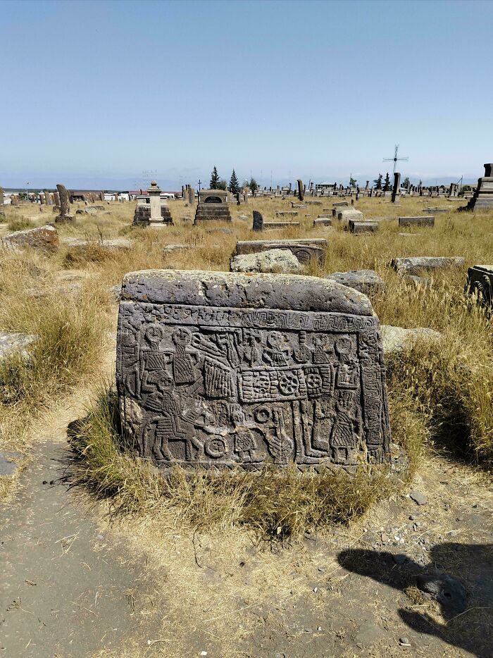 Old carved stone monument with intricate designs in a grassy ancient graveyard