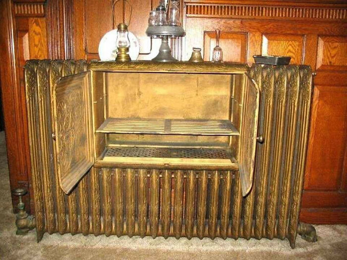 Antique vintage food smoker or oven with open golden doors inside a wooden room