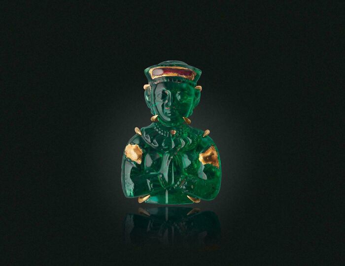 Small emerald green ancient figurine with gold details from a historic era discovery