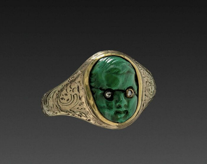 Ancient engraved gold ring with emerald carved face and gemstones as eyes discovery