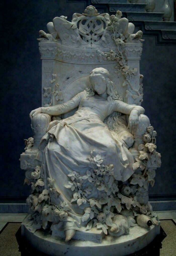 Detailed marble sculpture of a seated woman adorned with floral motifs