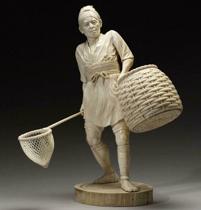 Detailed ivory carving of a man carrying a basket and fishing net