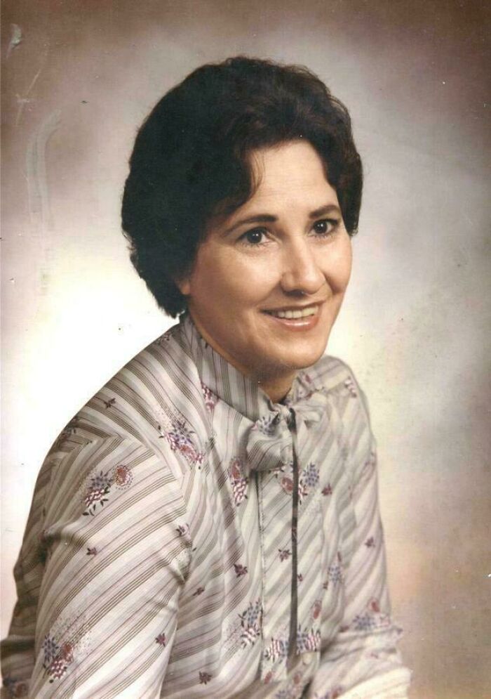 Emotional historical photo of a smiling woman with dark hair in a patterned blouse, capturing the past.