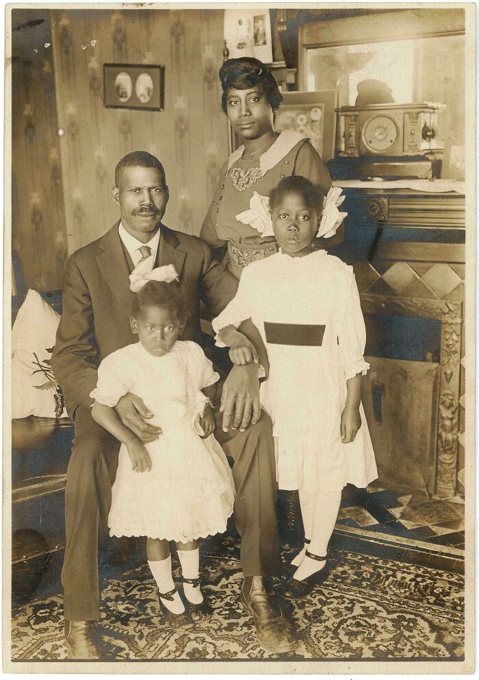 Fascinating historical photos of an African American family, including parents and two daughters in white dresses, posing indoors.