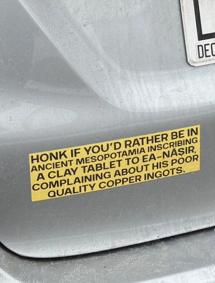 An unfiltered bumper sticker that reads, HONK IF YOU'D RATHER BE IN ANCIENT MESOPOTAMIA INSCRIBING A CLAY TABLET TO EA-NASIR COMPLAINING ABOUT HIS POOR QUALITY COPPER INGOTS.